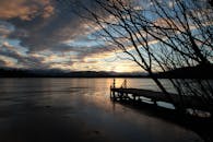 宁静的湖面上，日落静谧，映衬着码头和树木的轮廓