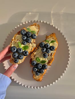 Delicious blueberry and butter toast on a plate held by a person, perfect for breakfast inspiration.