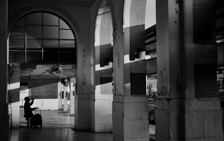 Silhouette Of A Person Sitting And Drinking In Urban Building In Black And White