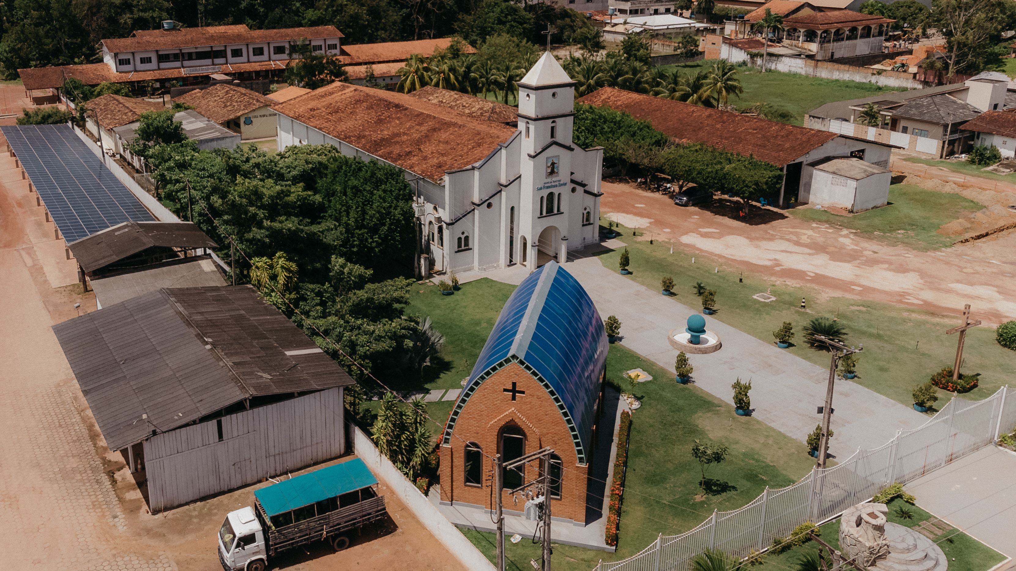 Drone shot of a church surrounded by rural architecture and greenery.