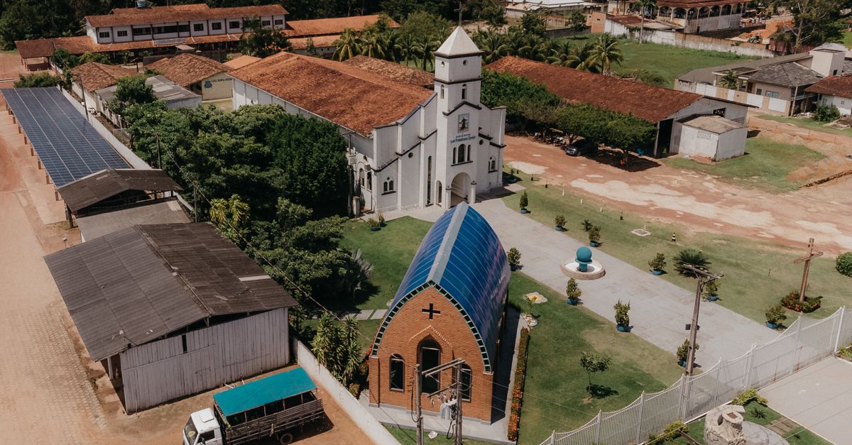 Drone shot of a church surrounded by rural architecture and greenery.