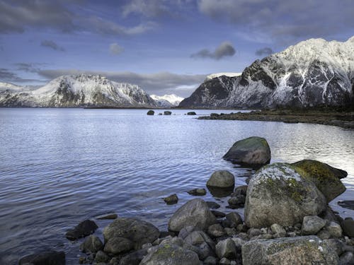 Black and Gray Rock Formations Beside Blue Body of Water