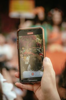 Close-up of a smartphone recording a vibrant city street scene in Adana, Turkey.