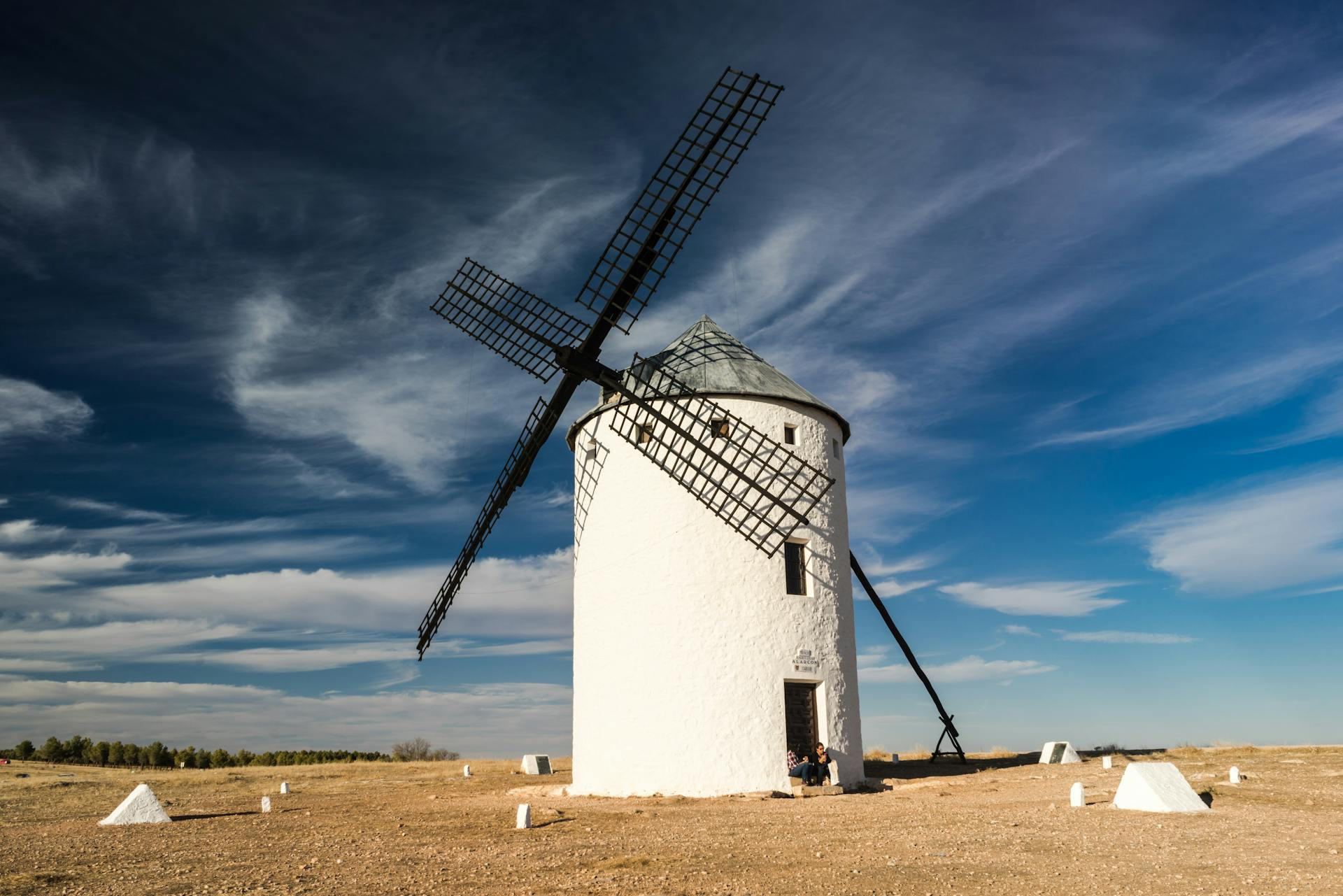Scenic view of a traditional white windmill against a vibrant blue sky on a clear day.