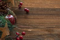 乡村圣诞装饰品中，木桌上摆放着松果和红色浆果