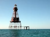 一座高耸的金属灯塔孤立地矗立在晴朗天空下的海洋中