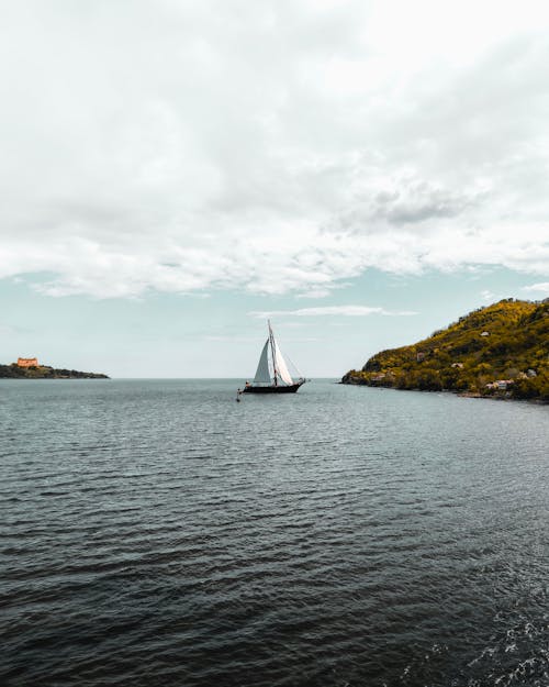 A sailboat is sailing on the water near a small island
