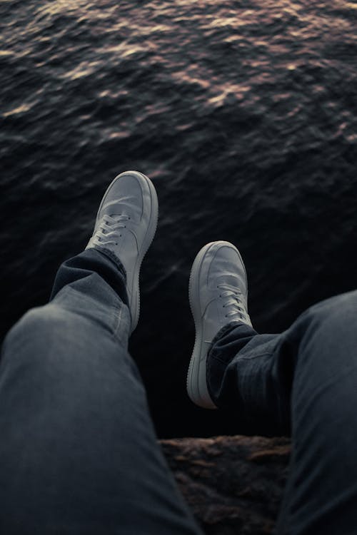 A person's feet are on a ledge with the ocean in the background