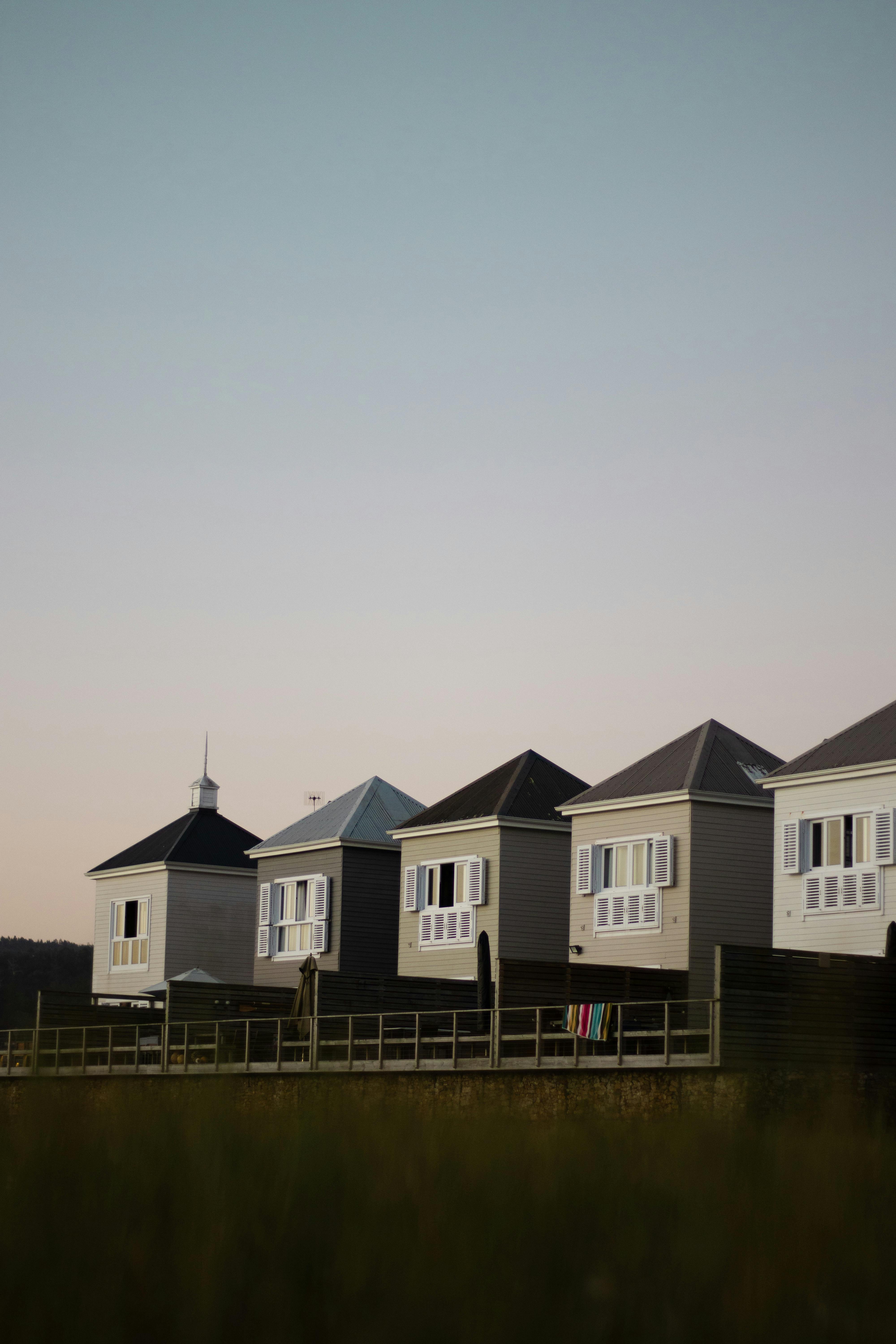Row of contemporary coastal cabins with clear sky at sunset, perfect for travel and architecture enthusiasts.