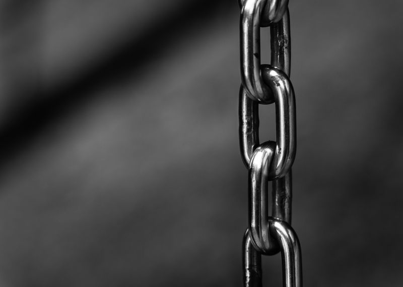 Close-up of a polished metal chain link with blurred background
