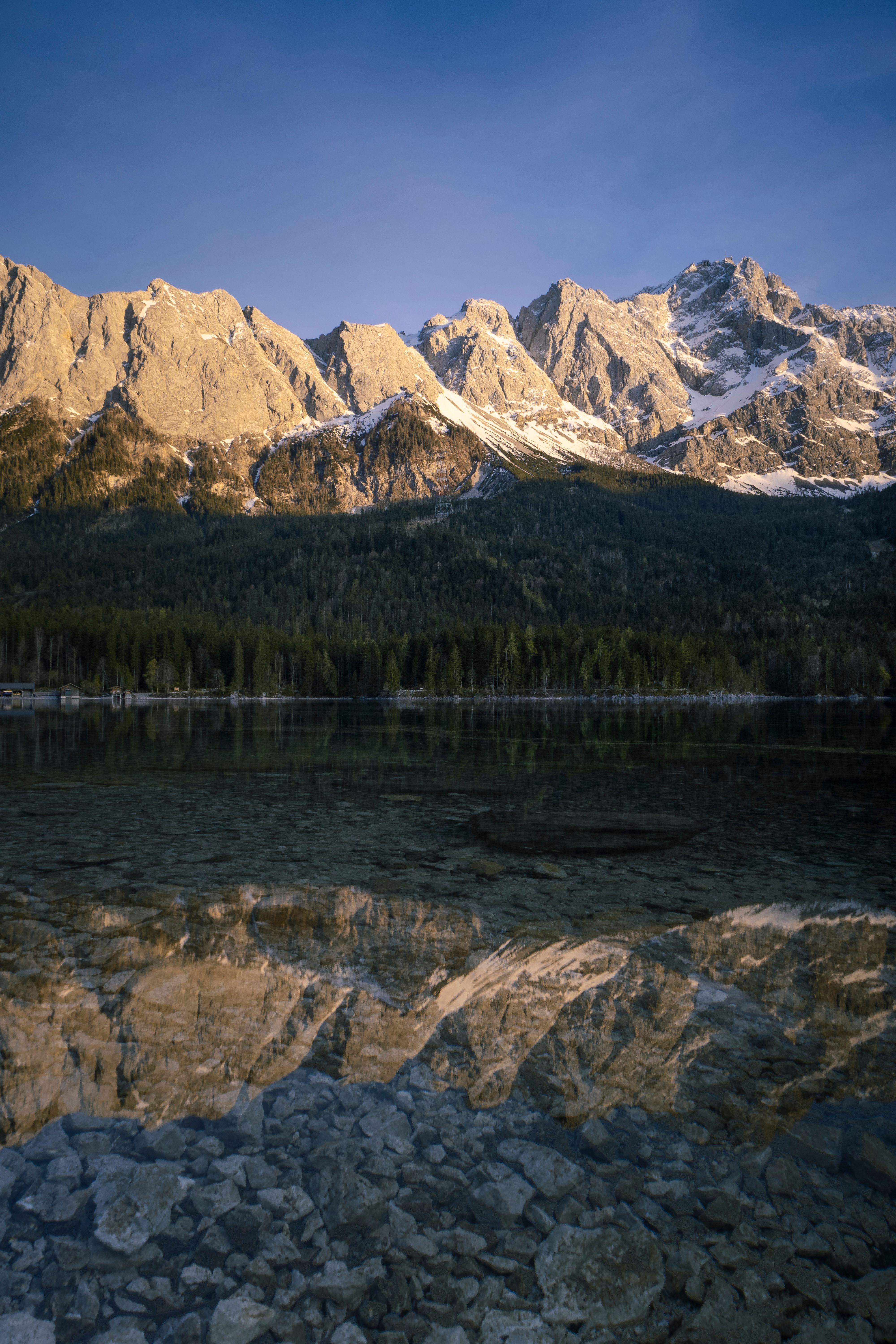 A stunning view of rugged mountains reflected in a serene lake at sunrise, capturing the beauty of nature.