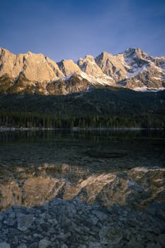 A stunning view of rugged mountains reflected in a serene lake at sunrise, capturing the beauty of nature.