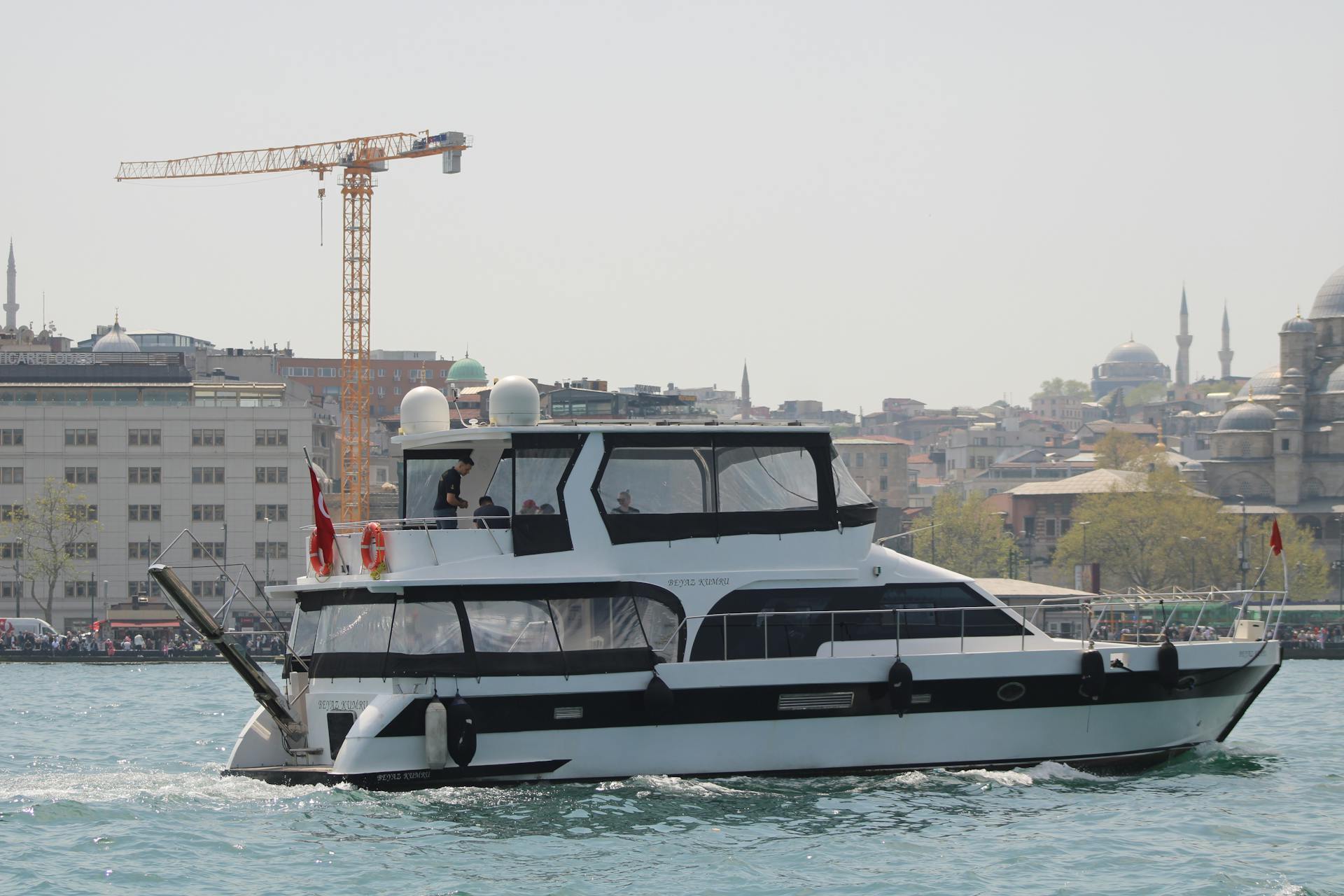 Motor yacht sailing on the Bosphorus with Istanbul skyline and landmarks in the background.