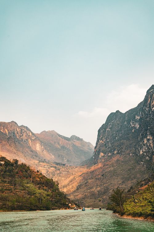 Free Picturesque Hà Giang valley with lush mountains and serene river under a clear sky. Stock Photo