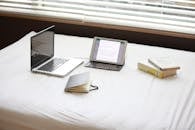 Macbook Pro over White Fabric Sheet Beside White Ipad