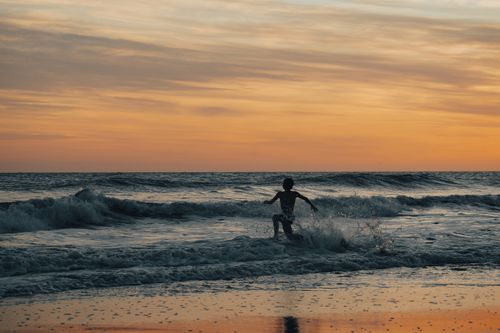 Free A lone silhouette runs through ocean waves, capturing the essence of freedom and adventure. Stock Photo