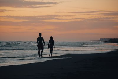 Two people walking along a shoreline at dusk, photo by Gaspar Zaldo on Pexels