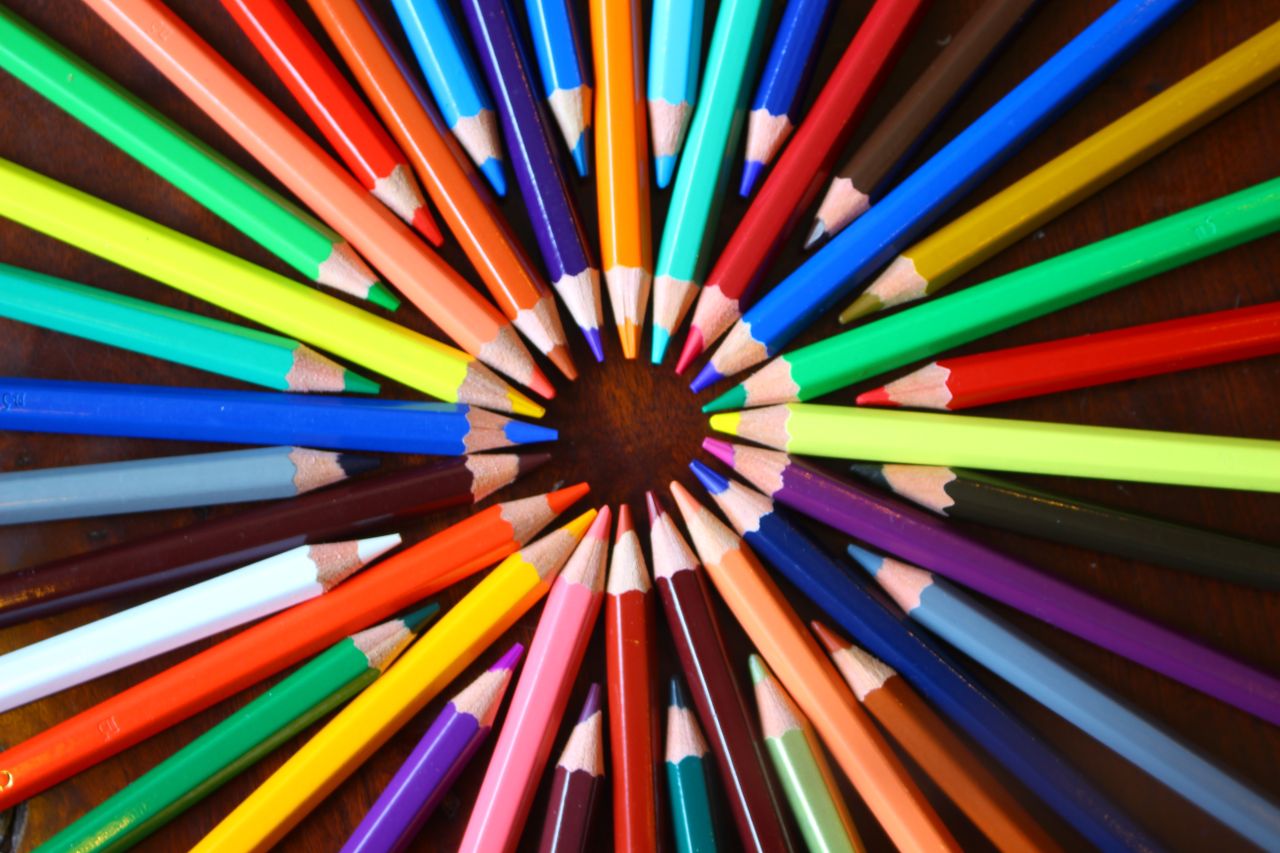 vibrant spiral of colored pencils forming a rainbow spectrum on a wood