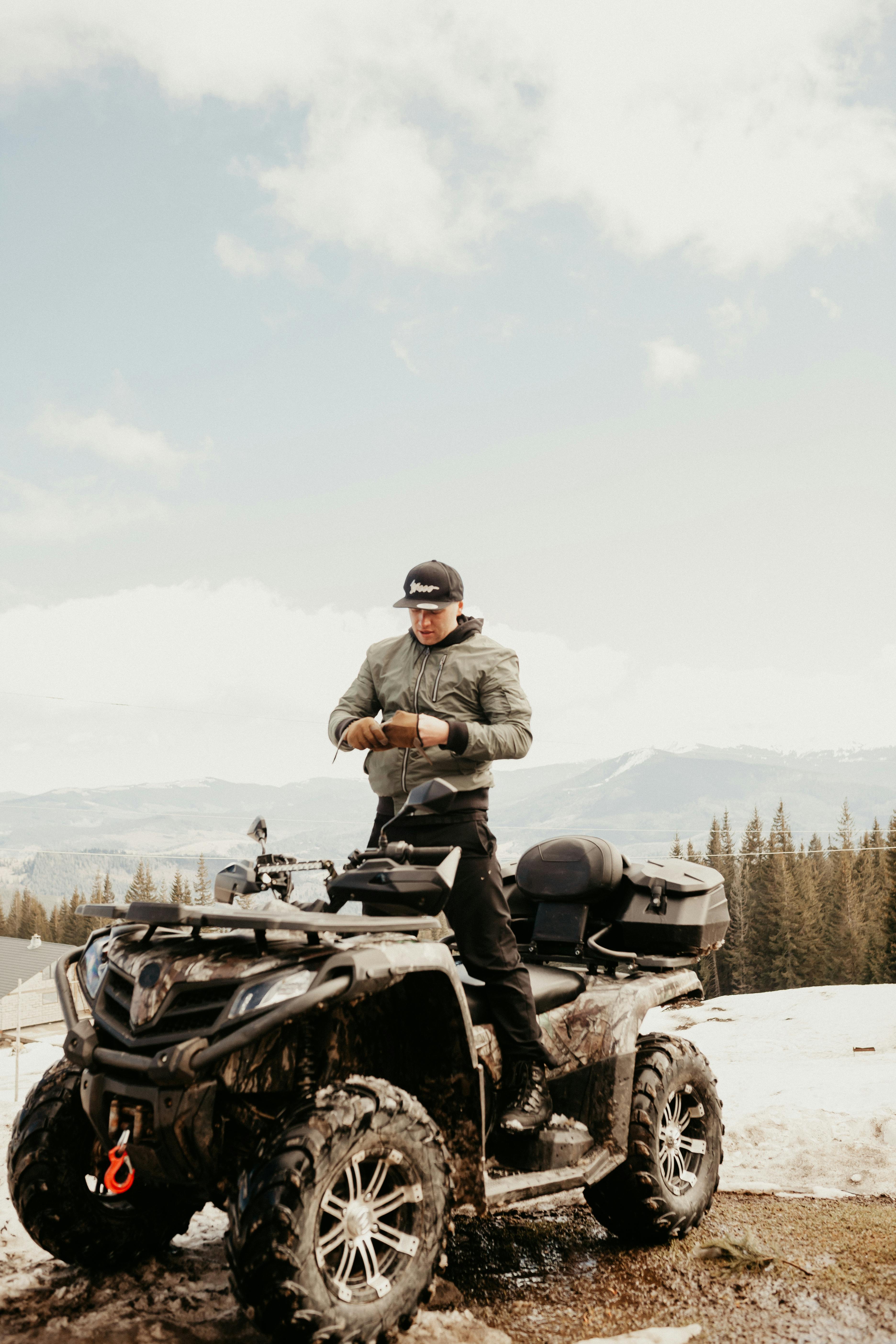 Man enjoying a winter adventure on ATV in snowy mountainous landscape.
