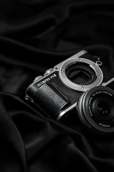 Close-up of a vintage-style mirrorless camera with lens on elegant black fabric.