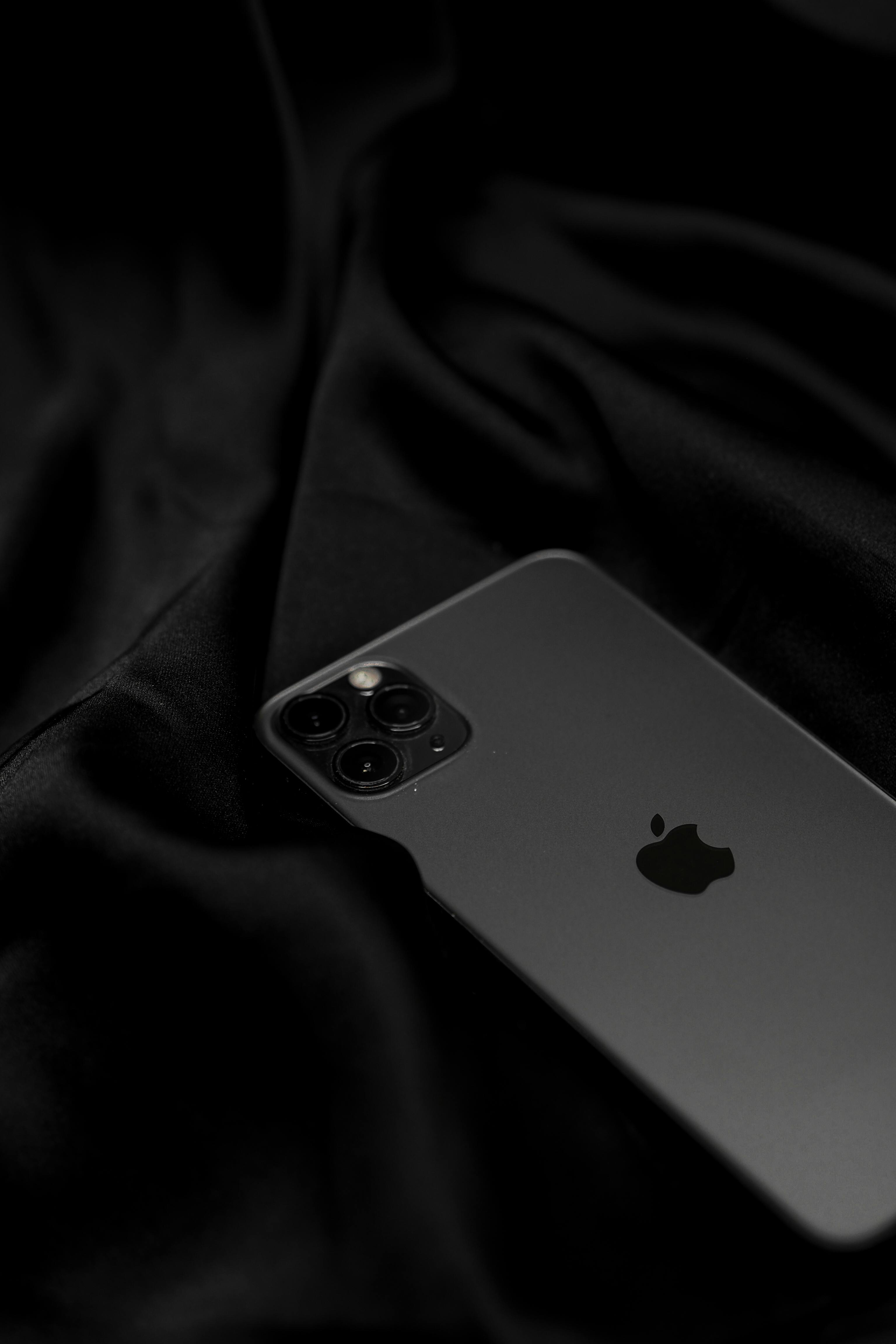 Stylish black smartphone on sleek satin fabric, showcasing modern technology design.