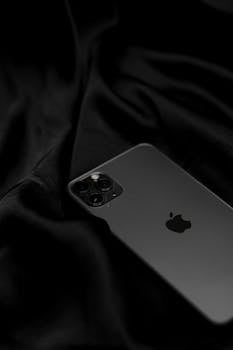 Stylish black smartphone on sleek satin fabric, showcasing modern technology design.