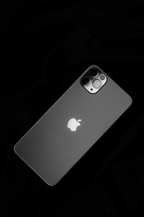 Free Sleek smartphone resting on a black background, showcasing modern technology. Stock Photo