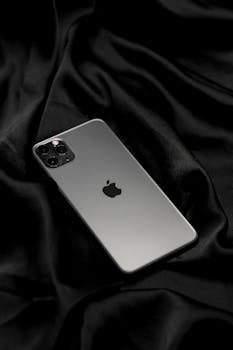 Elegant smartphone placed on smooth black satin fabric, showcasing modern technology and design.