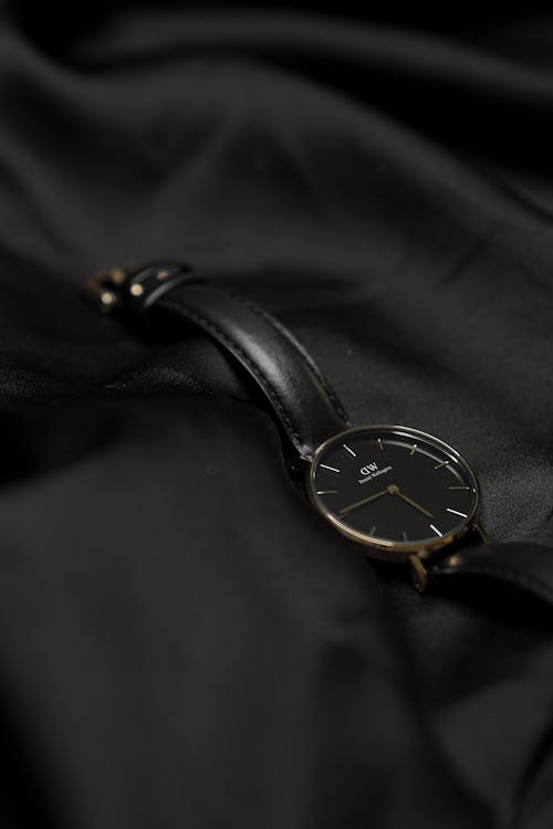 A black and gold watch laying on a black cloth