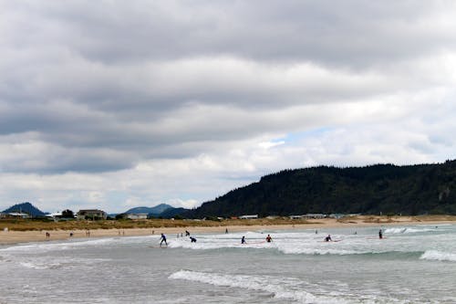 People on Beach Under Grey Cloudy Sky