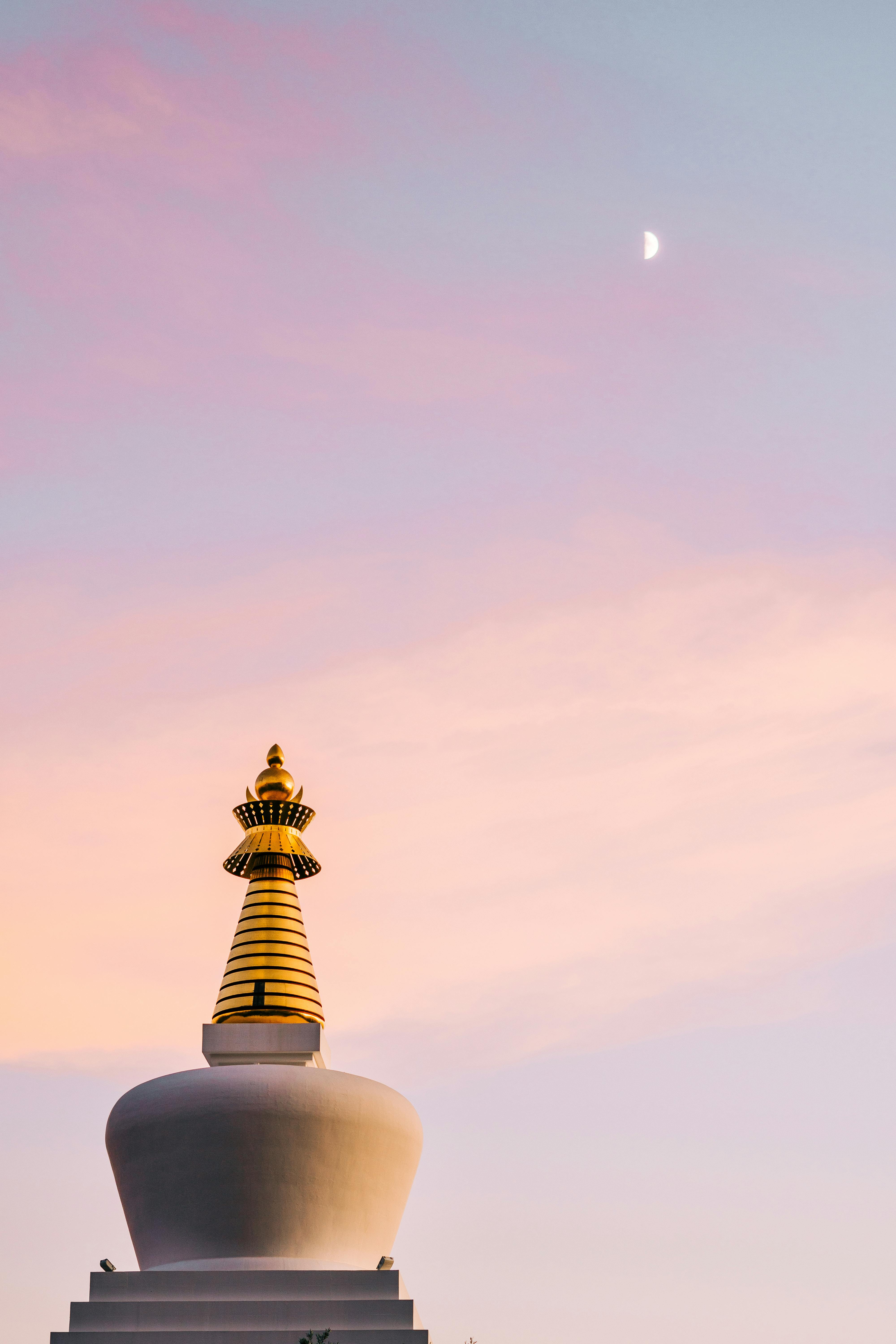 Peaceful view of the Stupa of Enlightenment under a crescent moon at dusk in Benalmádena, Spain.