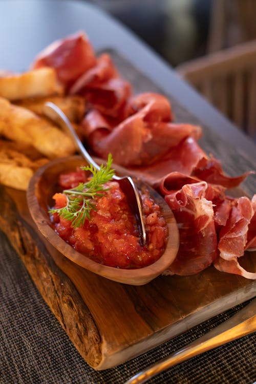 A wooden cutting board with meat and bread