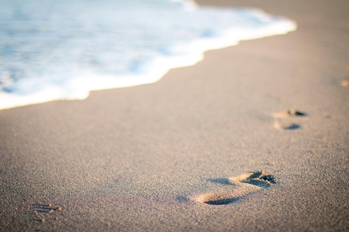 Footprints in the wet sand as the water comes in - The Source of Love and His Footsteps