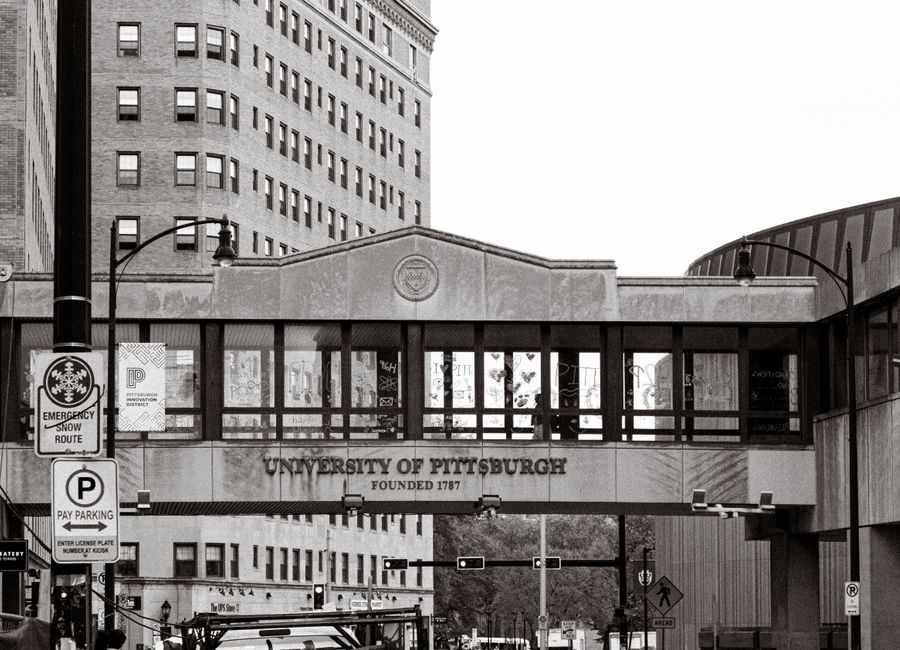 Historic University of Pittsburgh campus street view with iconic architecture in black and white.