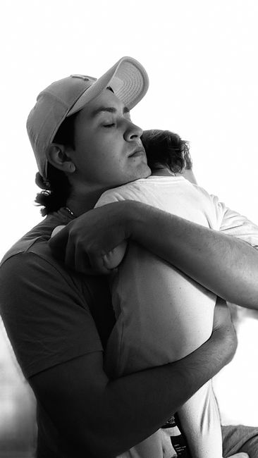A touching black and white portrait capturing a father's loving embrace of his newborn baby.