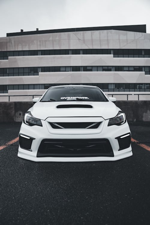 A white subaruna parked in front of a building