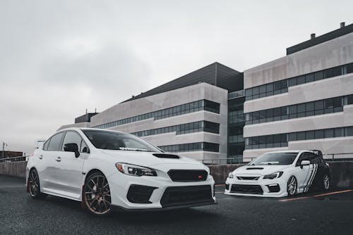 Two white subaruna cars parked in front of a building