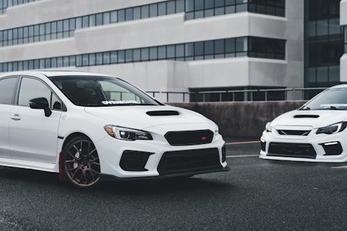Two white subaruna cars parked in front of a building
