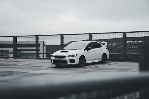 A white subaruna parked on a bridge