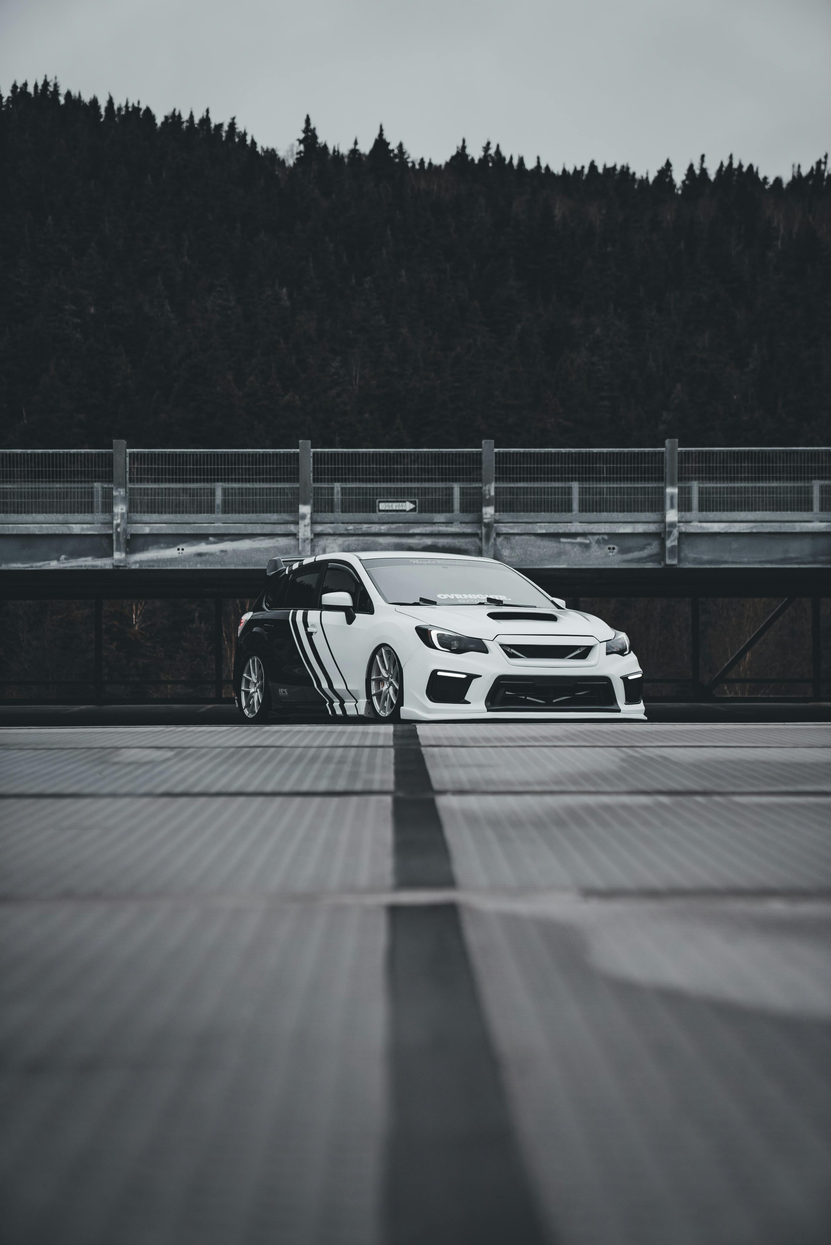 Free A white tuned Subaru sports car with custom livery parked on an urban rooftop, showcasing its sleek design. Stock Photo