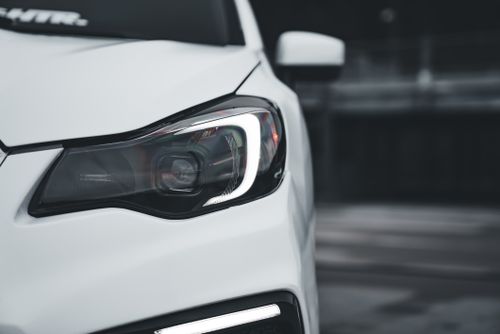 Free Close-up of a white sports car headlight with modern design and sleek lines, perfect for automotive enthusiasts. Stock Photo
