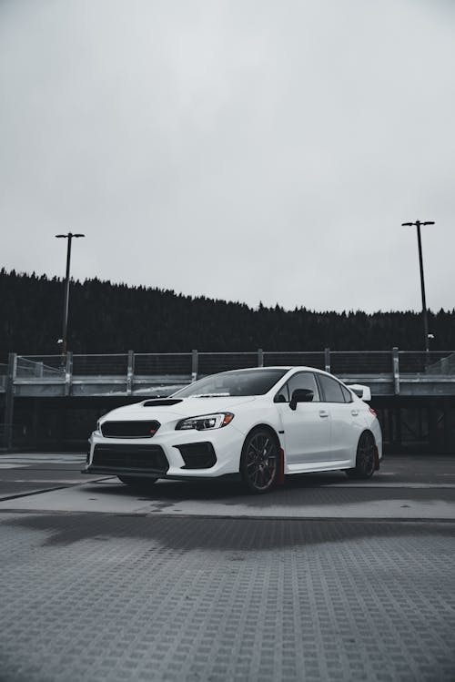 A white subaruna parked in front of a parking lot