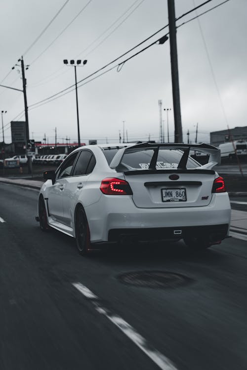 A white car driving down the road with a sign on it