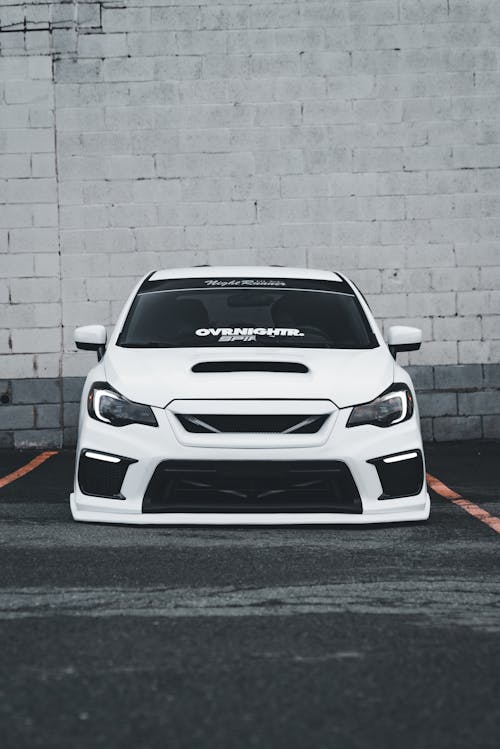 A white subaruna parked in front of a brick wall