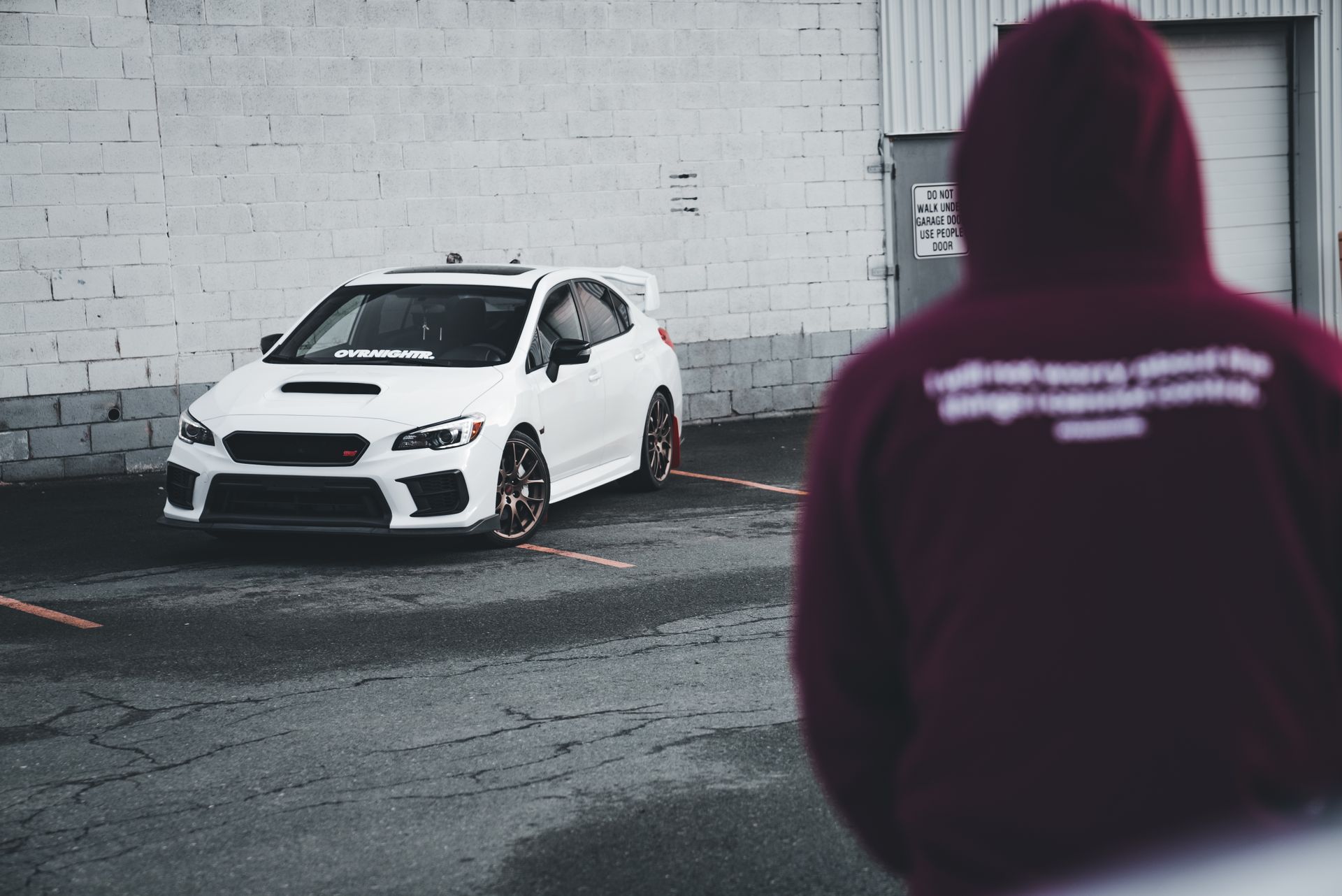 Man in Hoodie and Subaru WRX behind