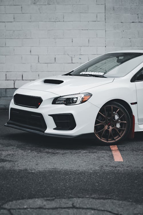 A white subaruna with red rims parked in a parking lot