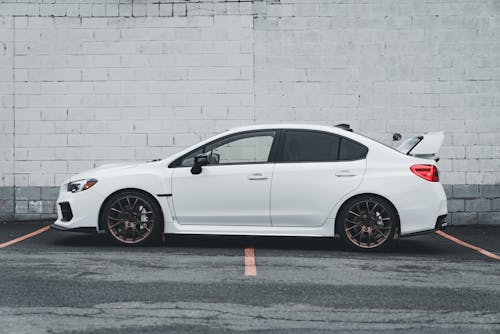 A white subaruna parked in front of a white wall