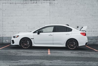 Side view of a white sports car parked by a brick wall — photo by Erik Mclean on Pexels