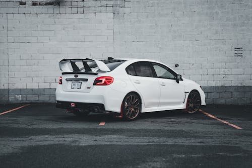 A white subaruna parked in front of a brick wall