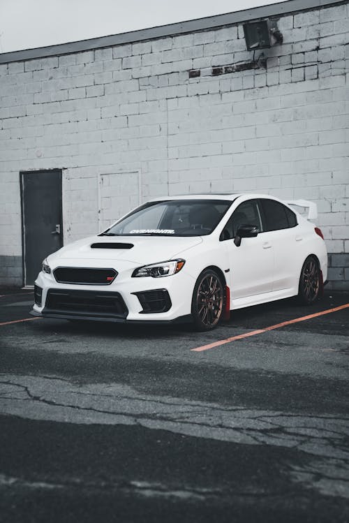 A white subaruna parked in front of a building